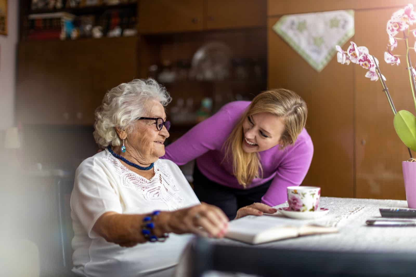 Elderly woman and caregiver sharing joyful moment at Lola's House.