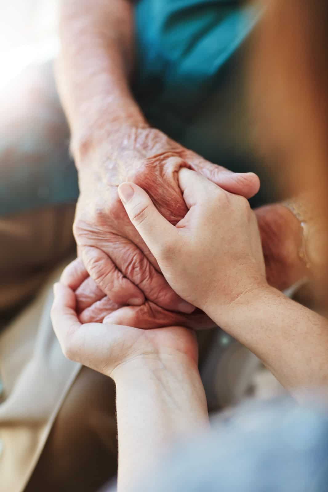 Elderly person holding hands with caregiver at Lola's House.