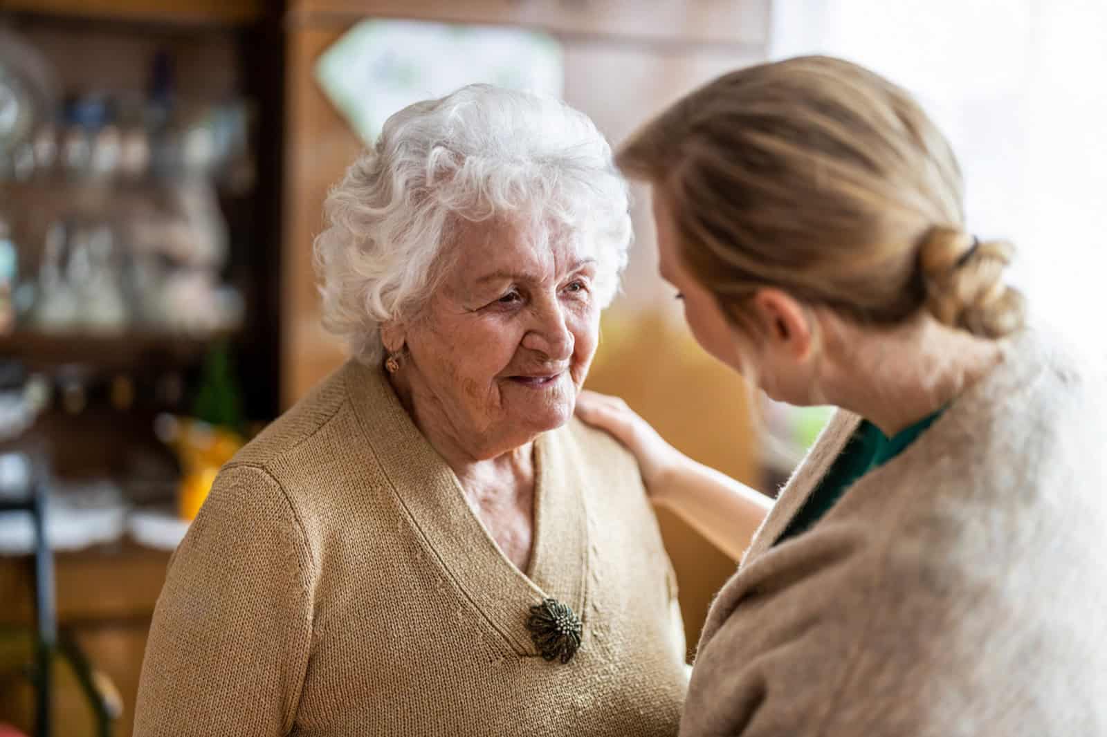 Elderly woman smiling with caregiver at Lola's House.