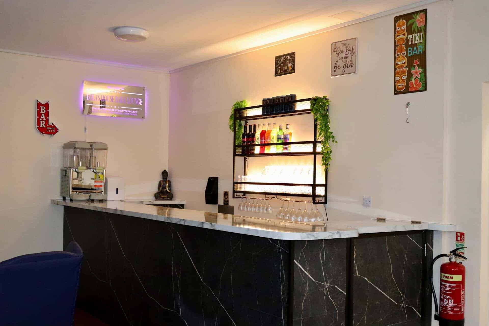 Modern bar area at Lola's House with tropical decor and drinks.