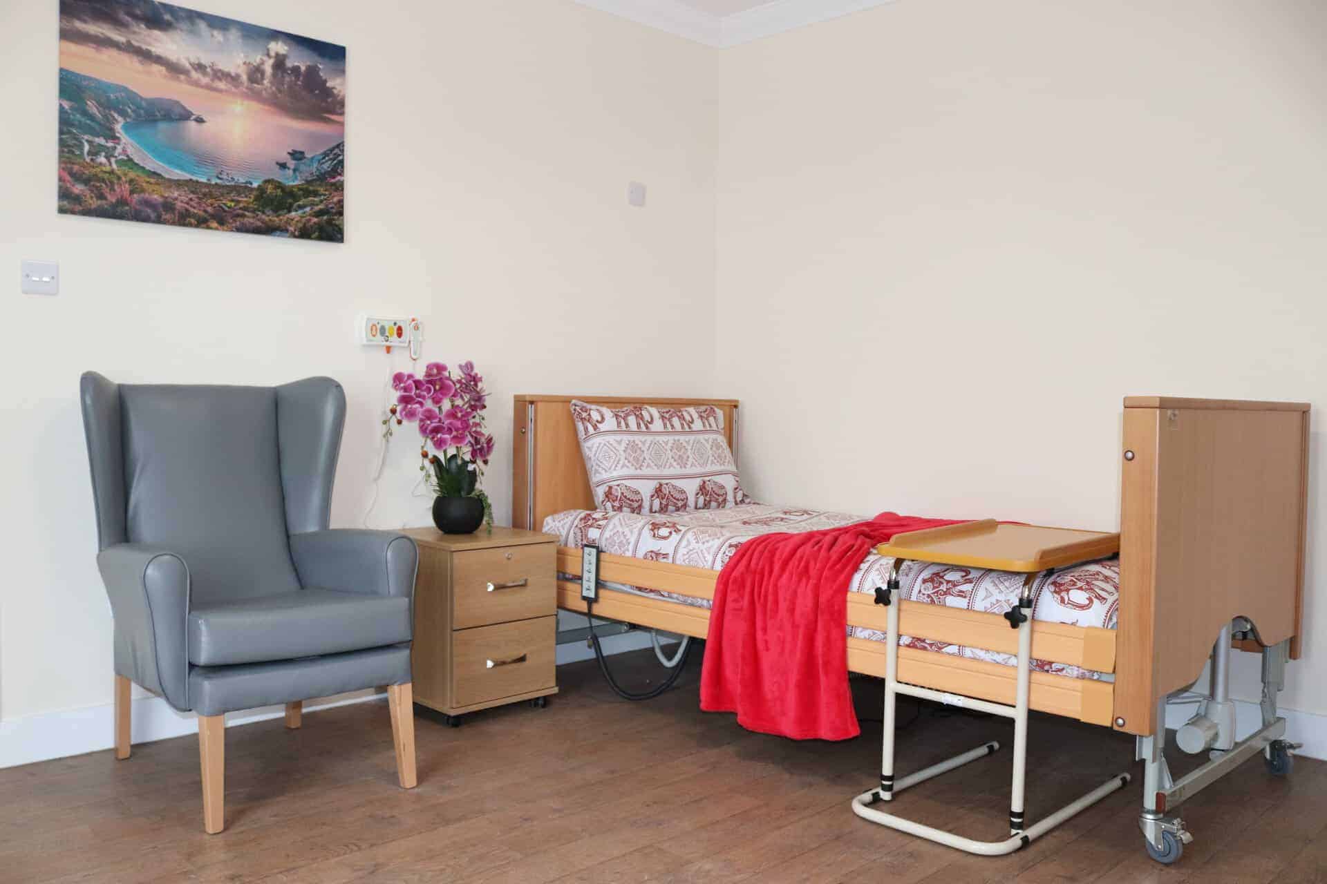 Hospital room with bed, armchair, and bedside table in Lola's House.