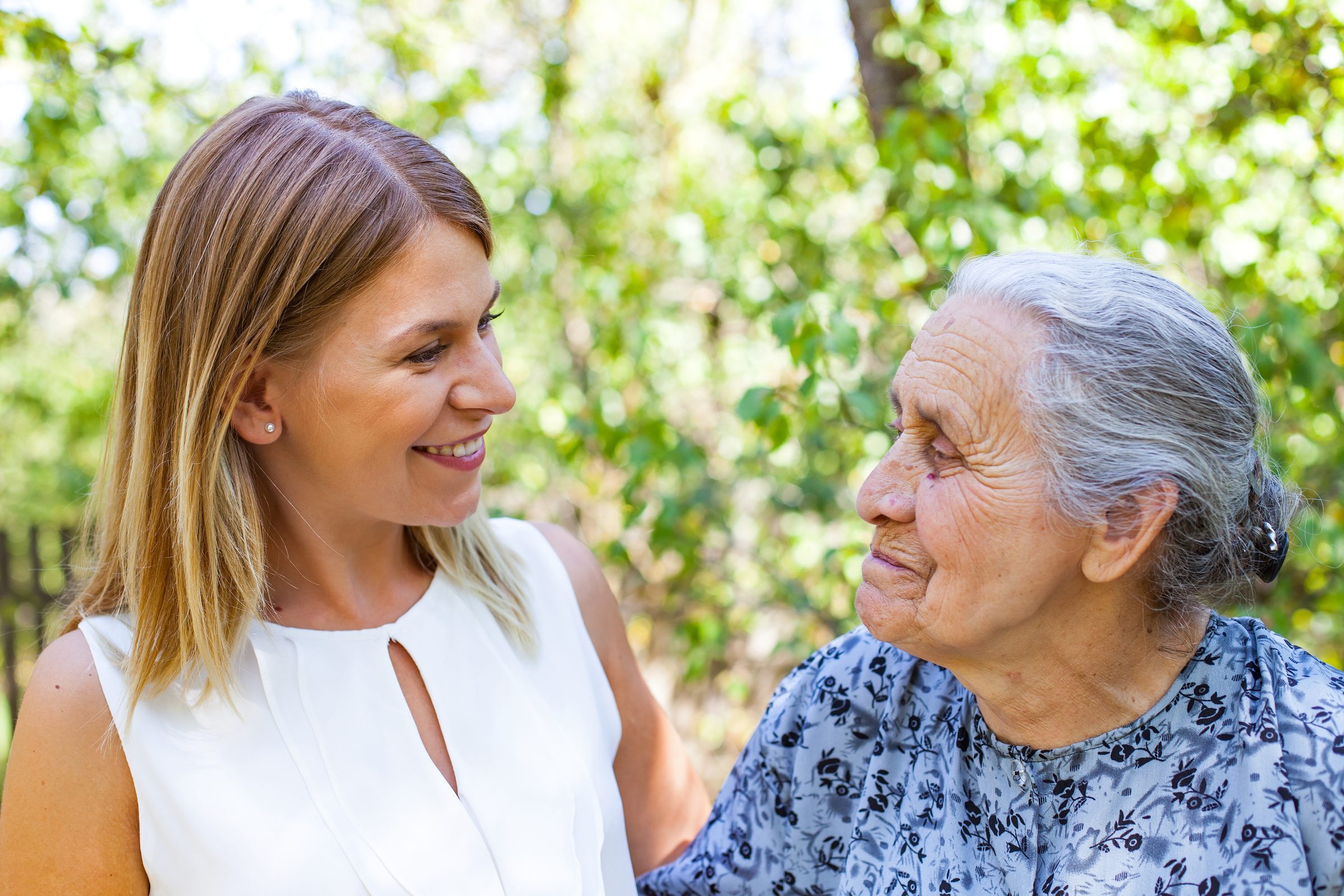 A carer and a resident smiling at each other in the garden